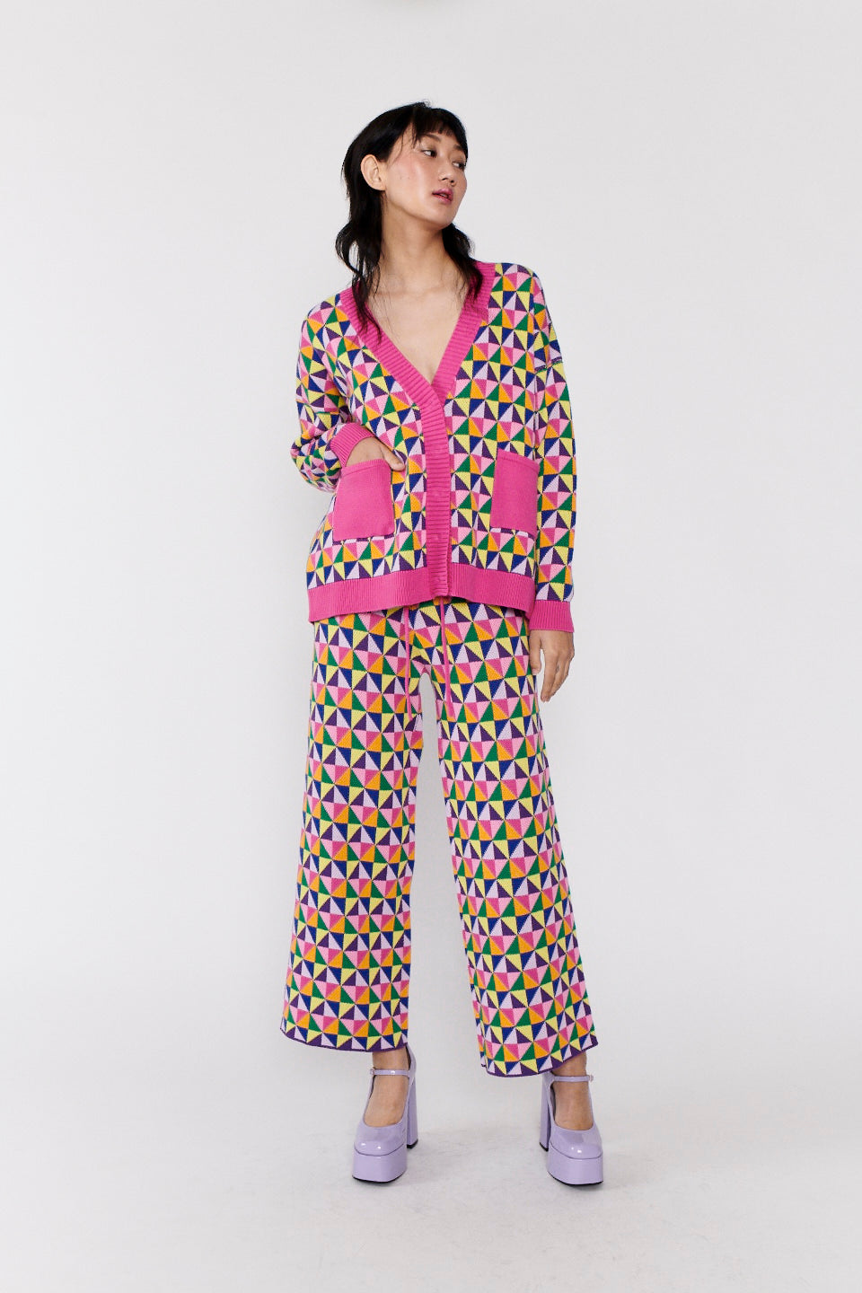 Magda longline cardigan in pink and multicolour origami pattern worn with matching knitted trousers