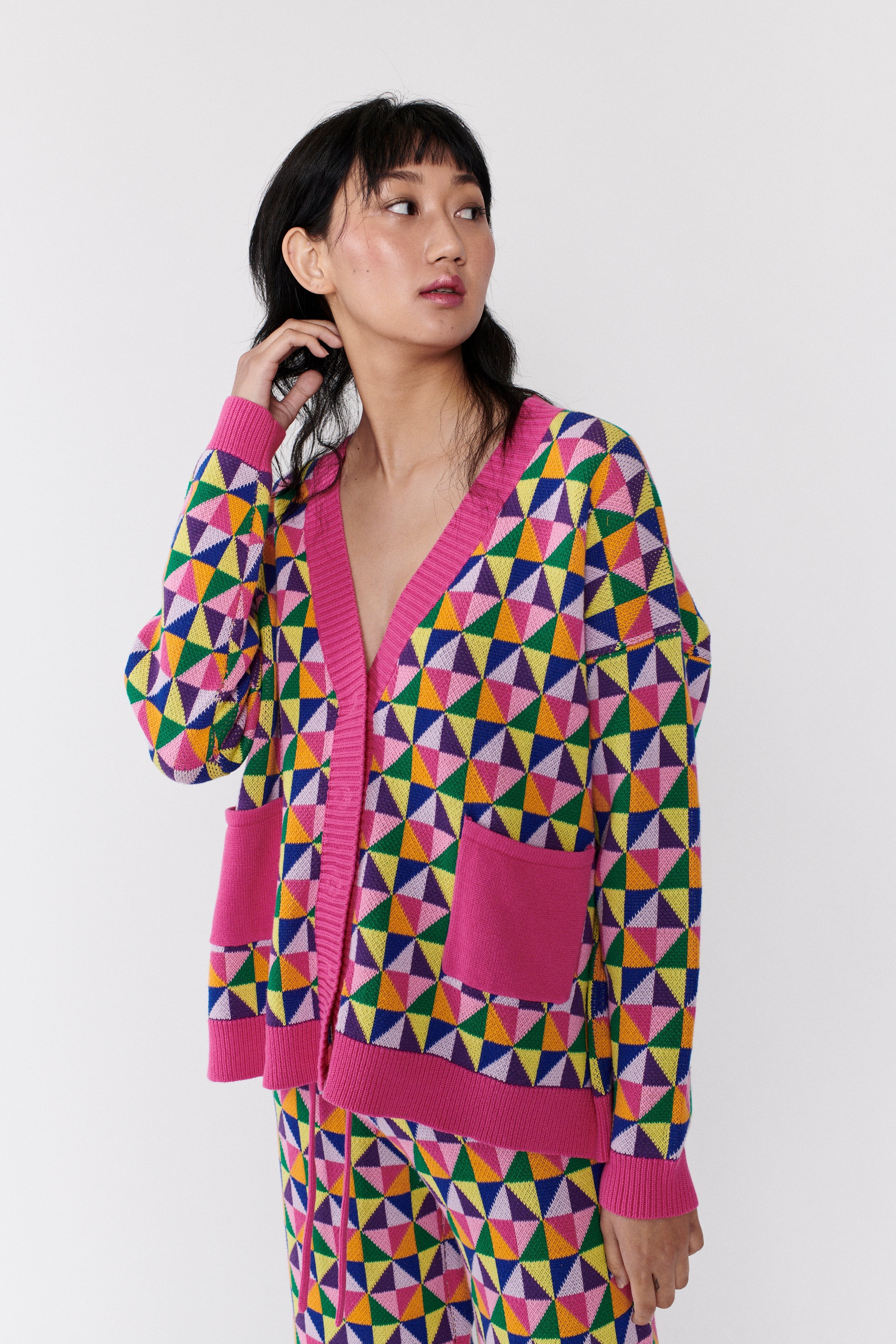 Model wears oversized Magda longline cardigan in pink and multicolour origami pattern with pockets