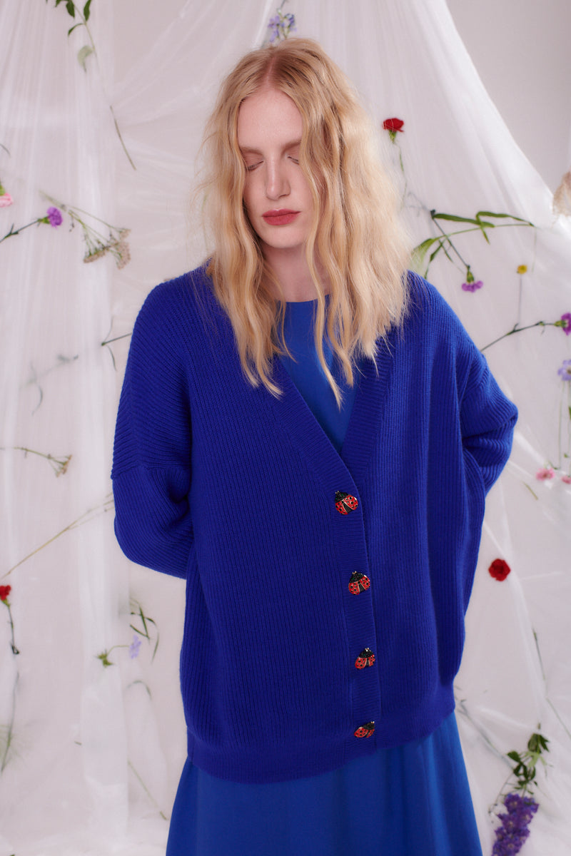 Model wears Olivia Rubin Frankie cardigan in blue with bejewelled ladybird buttons